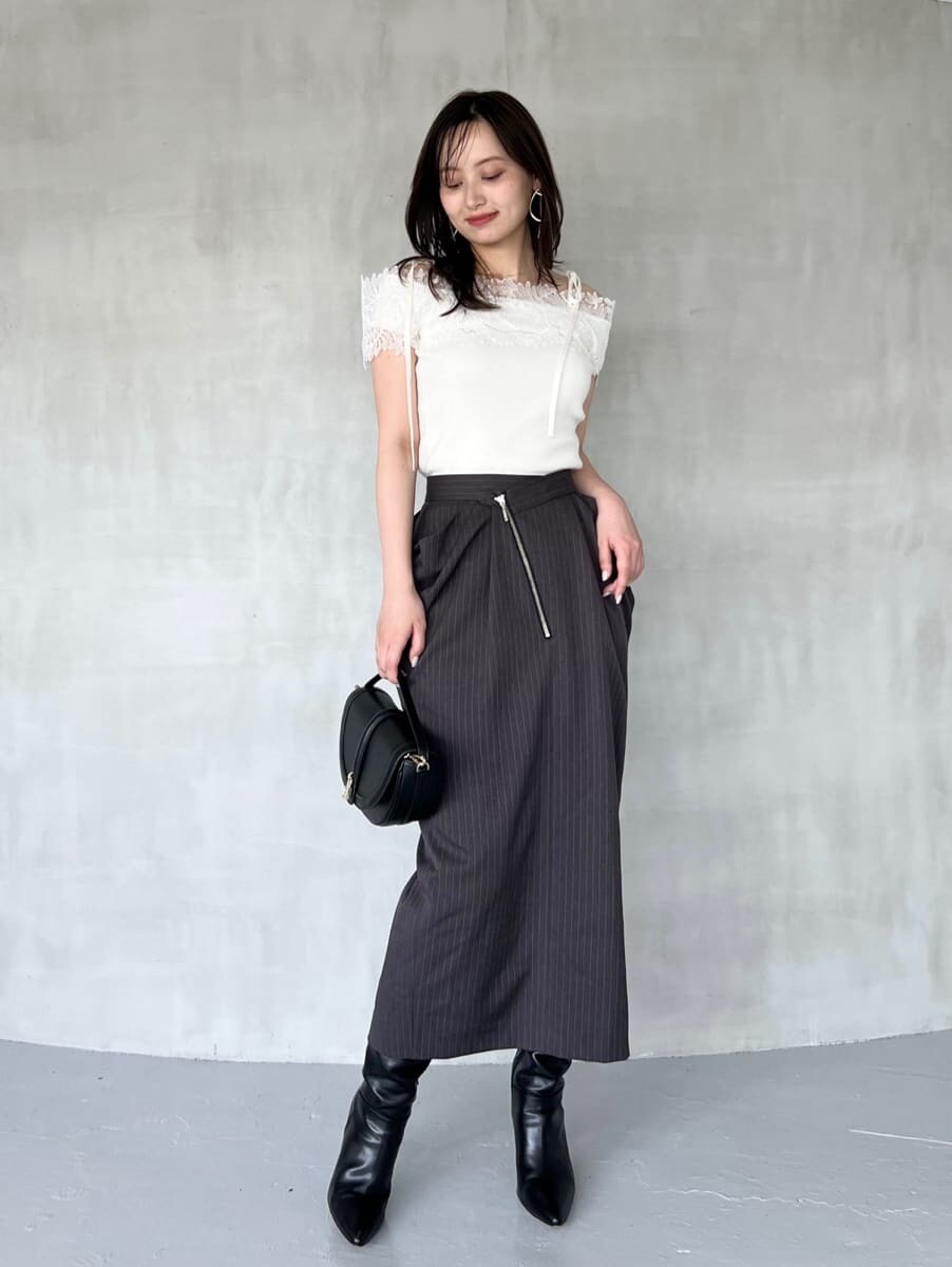 ホワイト系のニット/セーター、グレー系のスカート、ブラック系のブーツを着用したレディースの秋コーディネートの2枚目の写真