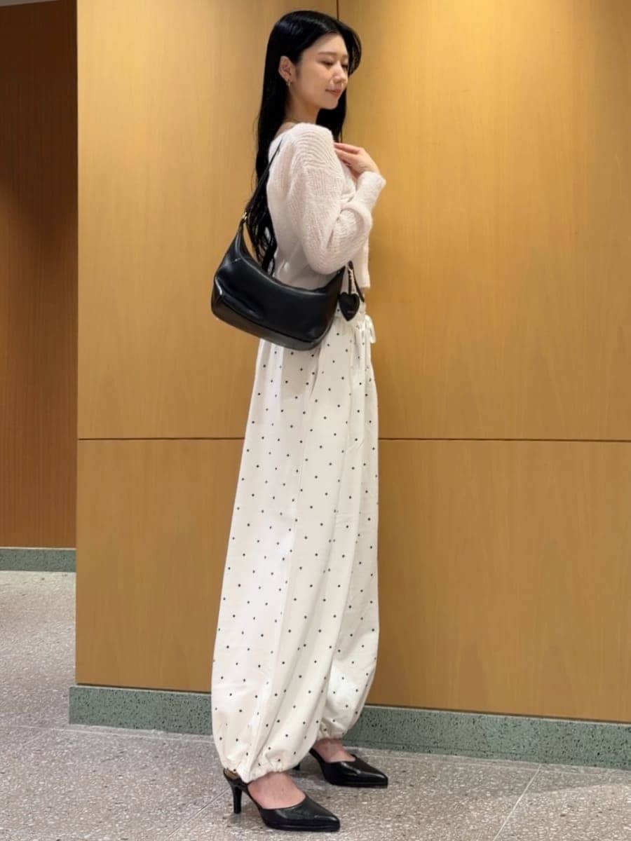 ピンク系のカーディガン/ボレロ、ブラック系のパンプス、ブラック系のショルダーバッグを着用したレディースの秋コーディネートの2枚目の写真
