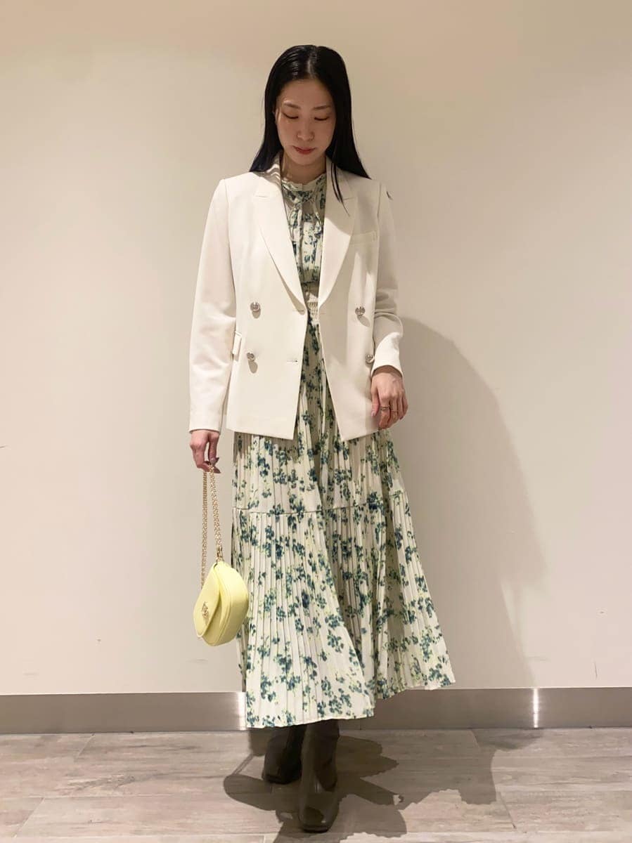 グリーン系のワンピース、ホワイト系のテーラードジャケット、イエロー系のショルダーバッグを着用したレディースの冬コーディネートの4枚目の写真
