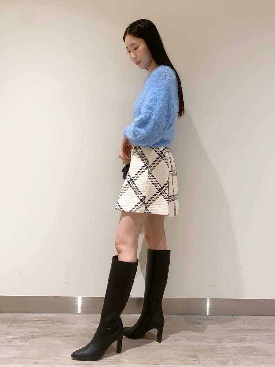 ホワイト系のスカート、ブラック系のブーツ、ブラック系のショルダーバッグを着用したレディースの冬コーディネートの3枚目の写真