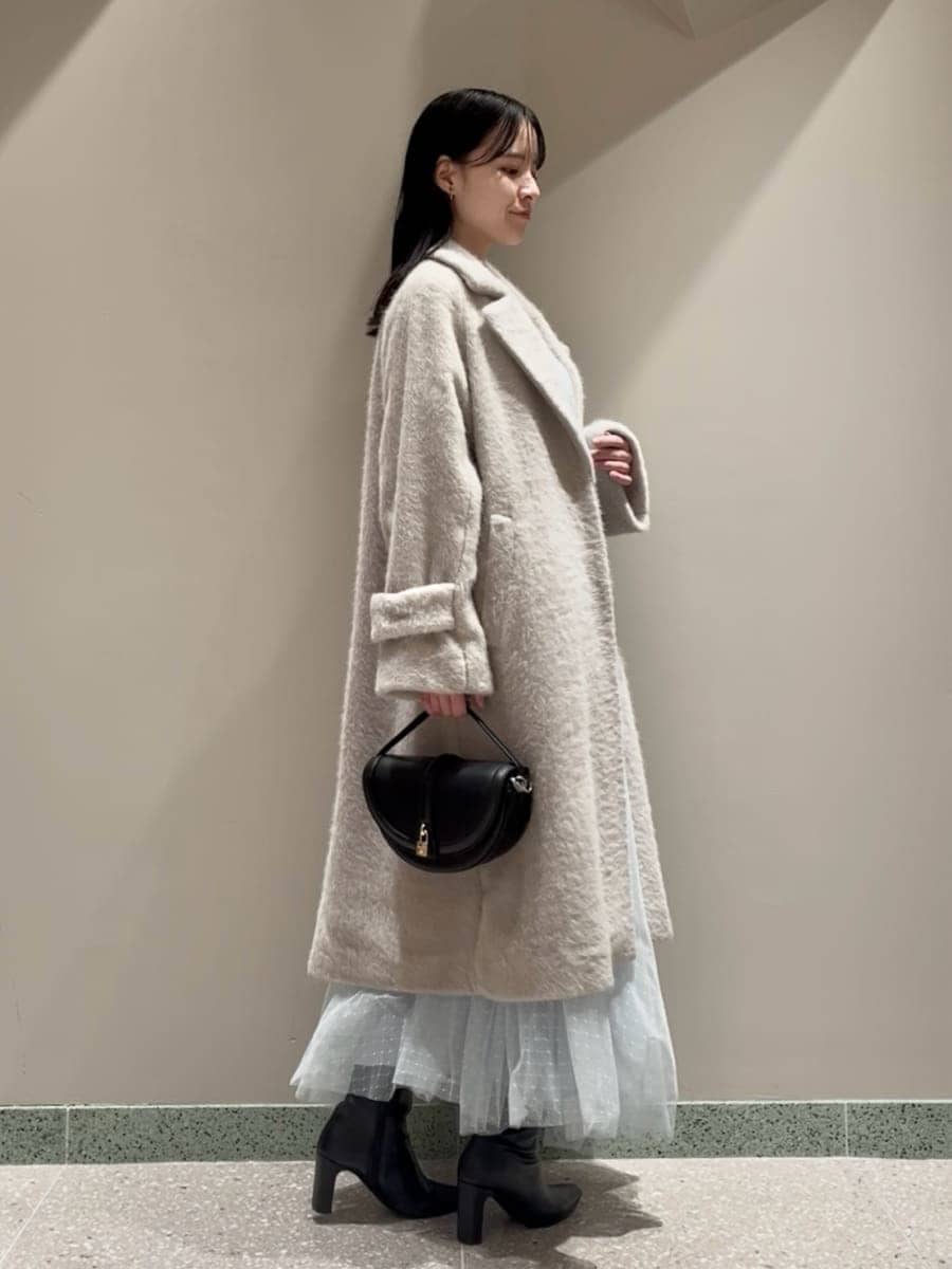 ブラック系のブーツ、ブラック系のハンドバッグ、ブルー系のワンピースを着用したレディースの冬コーディネートの2枚目の写真