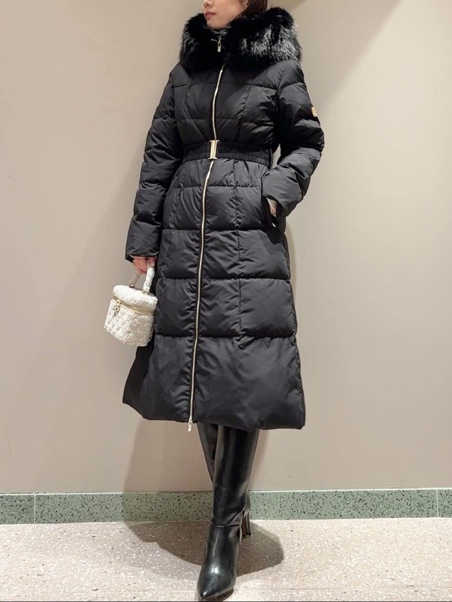 ホワイト系のニット/セーター、ブラック系のブーツ、ブラック系のダウンジャケット/コートを着用したレディースの冬コーディネートの2枚目の写真