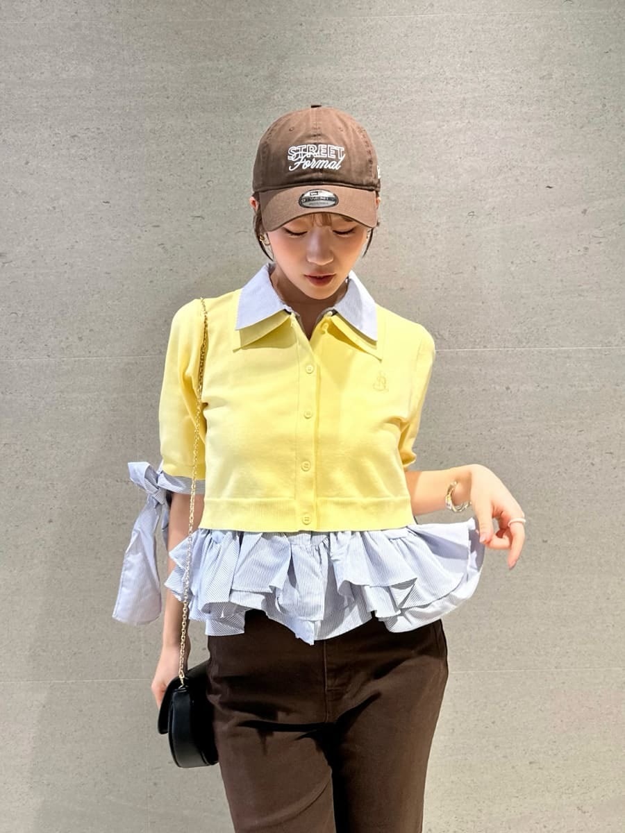 ブラック系のショルダーバッグ、ブラウン系のデニムパンツ、イエロー系のニット/セーターを着用したレディースの春コーディネートの5枚目の写真