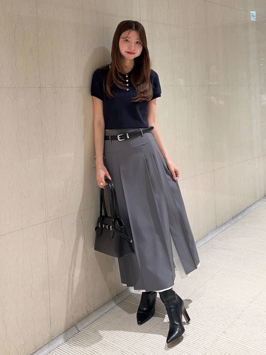グレー系のスカート、ブルー系のポロシャツ、ブラック系のブーツを着用したレディースの夏コーディネートの5枚目の写真