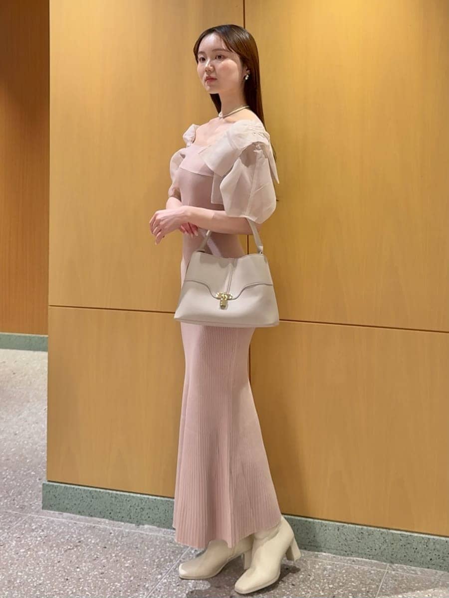 ピンク系のワンピース、ベージュ系のハンドバッグ、ホワイト系のネックレスを着用したレディースの春コーディネートの2枚目の写真