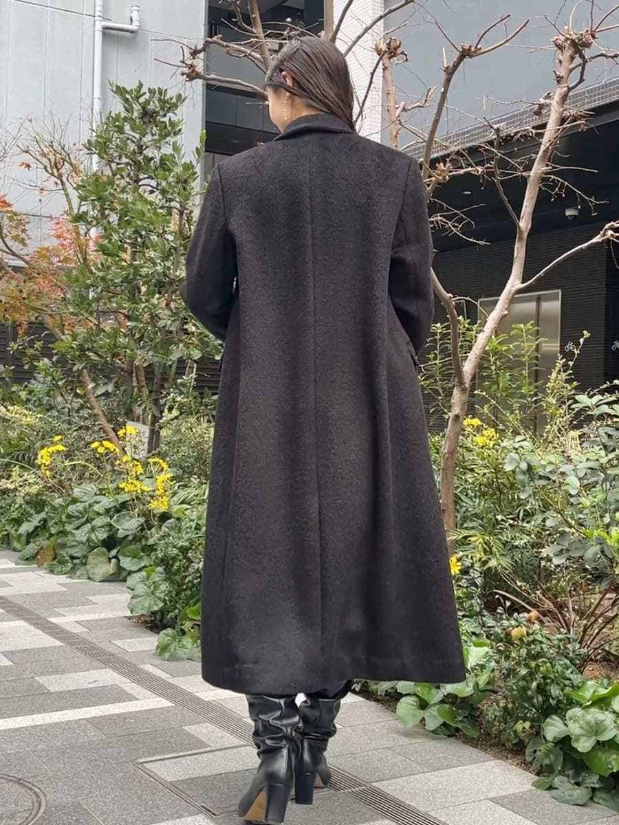 ブラック系のチェスターコート、グレー系のワンピースを着用したレディースの冬コーディネートの5枚目の写真