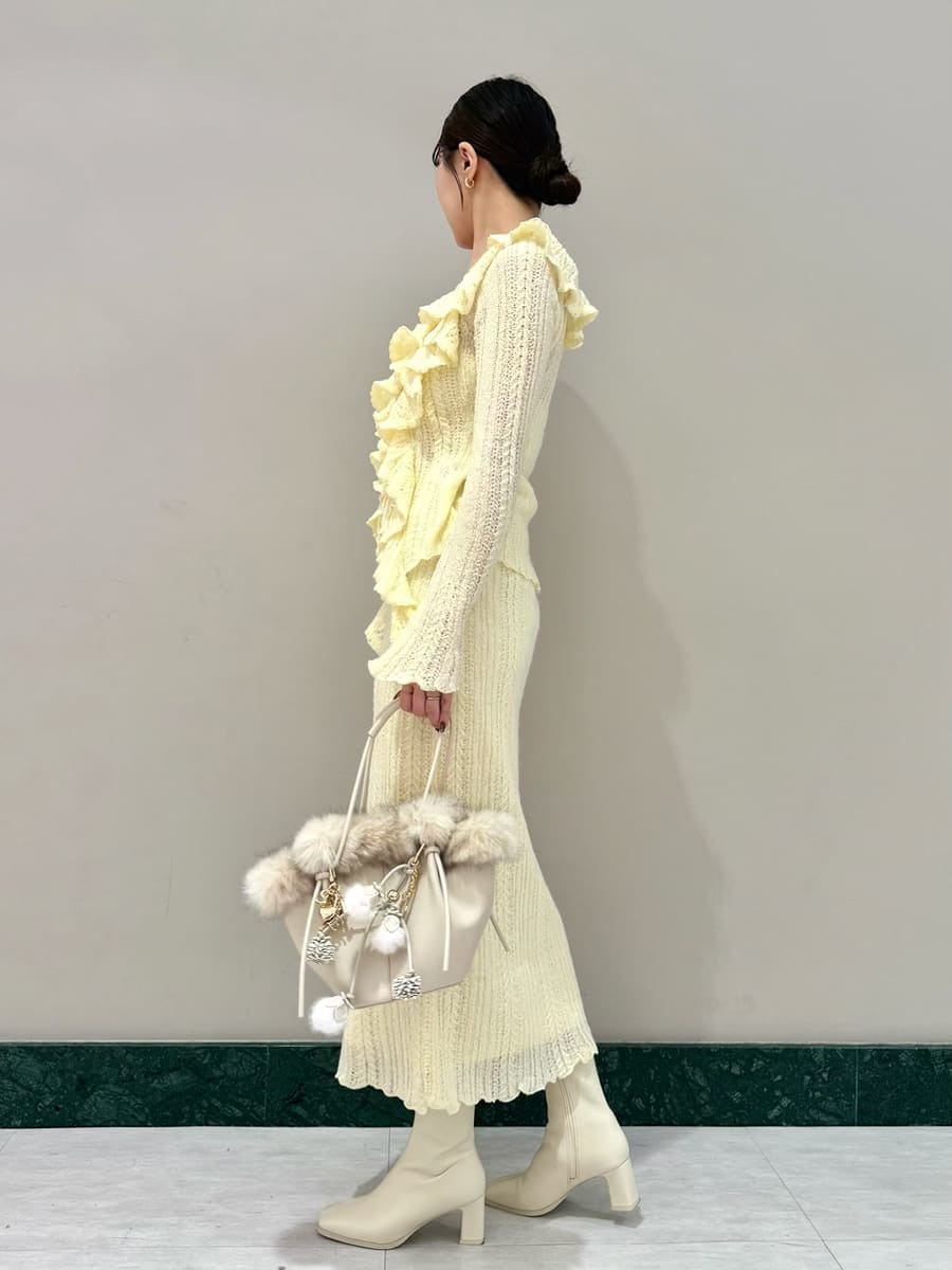 イエロー系のスカート、イエロー系のニット/セーター、ホワイト系のハンドバッグを着用したレディースの秋コーディネートの2枚目の写真