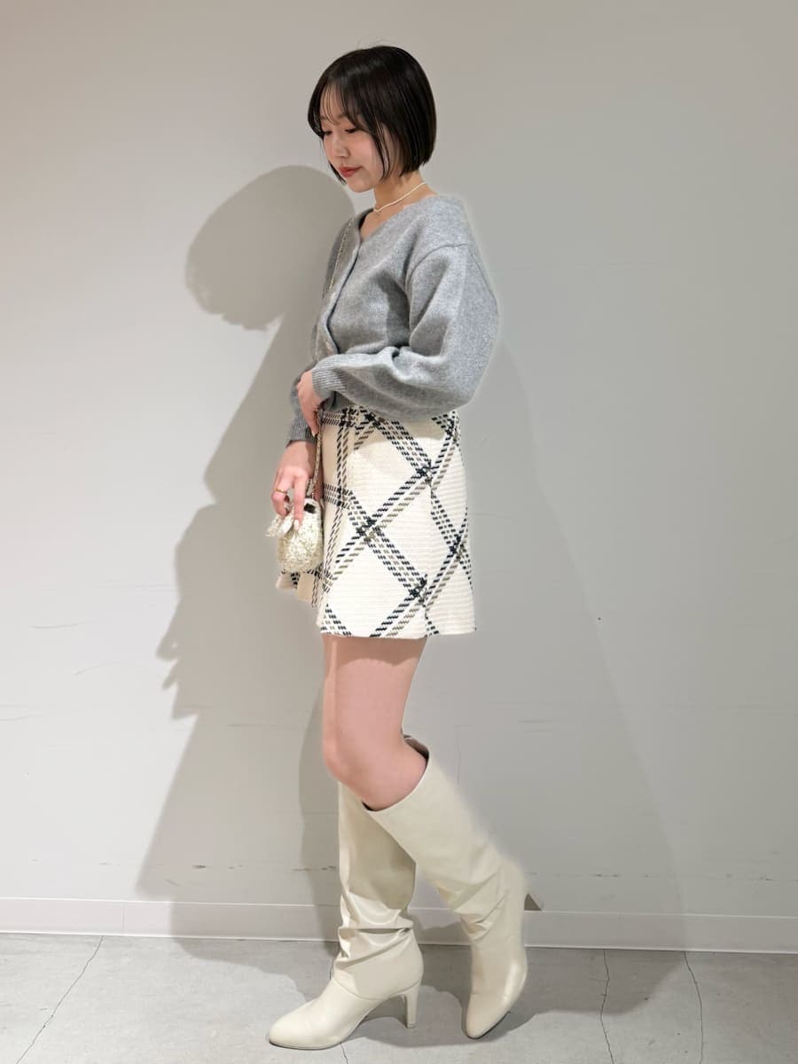 ホワイト系のスカート、グレー系のカーディガン/ボレロ、ゴールド系のキーケース/キーアクセサリーを着用したレディースの冬コーディネートの8枚目の写真