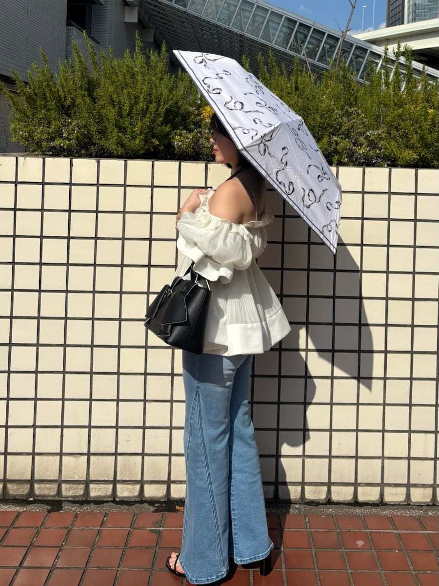 ブルー系のデニムパンツ、ホワイト系のその他トップス、ブラック系のハンドバッグを着用したレディースの春コーディネートの2枚目の写真