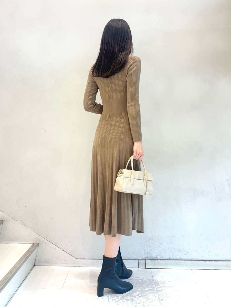 ホワイト系のチェスターコート、ベージュ系のワンピース、ホワイト系のボストンバッグを着用したレディースの秋コーディネートの5枚目の写真