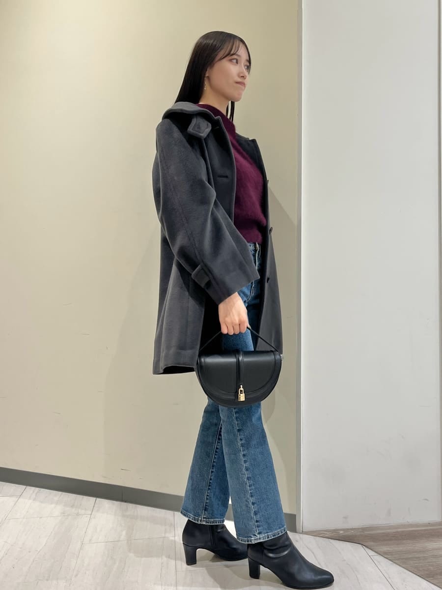 グレー系のステンカラーコート、レッド系のニット/セーター、ブルー系のデニムパンツを着用したレディースの秋コーディネートの2枚目の写真