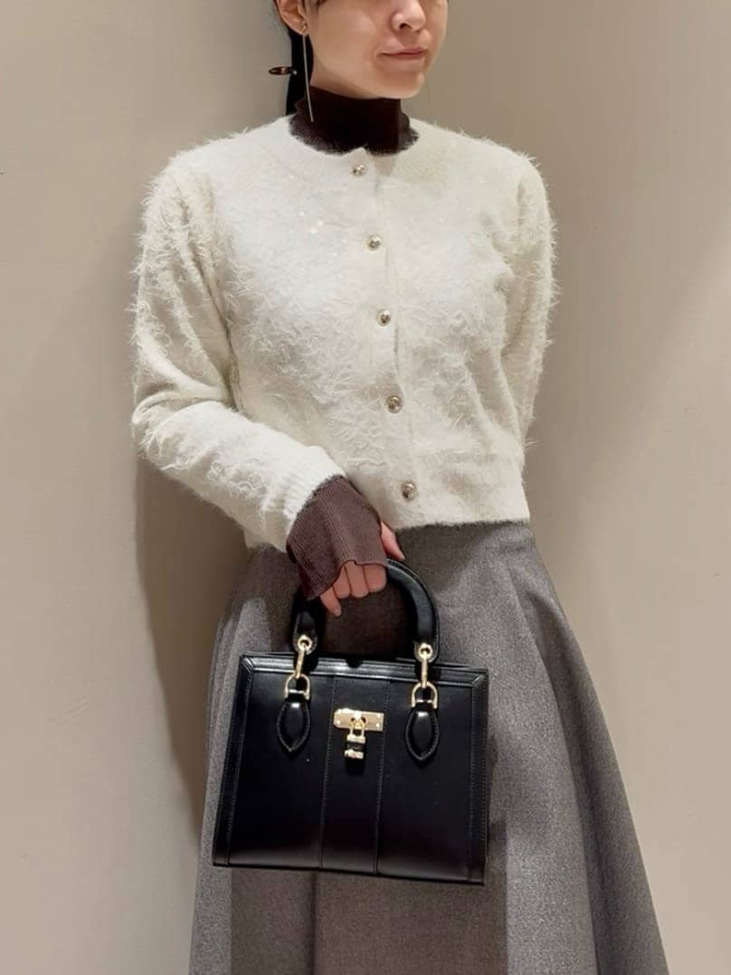 グレー系のスカート、ブラウン系のニット/セーター、ホワイト系のカーディガン/ボレロを着用したレディースの冬コーディネートの5枚目の写真
