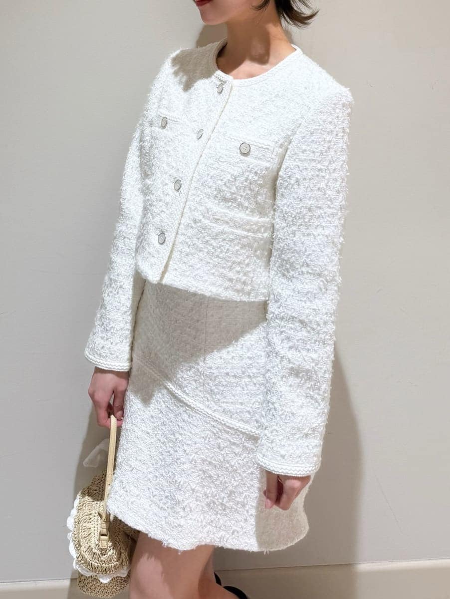 ブラウン系のブーツ、ホワイト系のノーカラージャケット、ホワイト系のスカートを着用したレディースの冬コーディネートの2枚目の写真