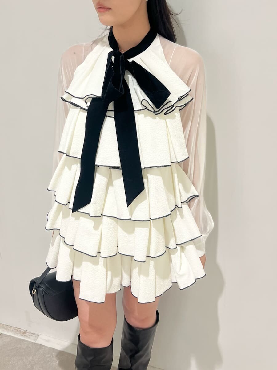 ブラック系のハンドバッグ、ホワイト系のドレス、ブラック系のブーツを着用したレディースの冬コーディネートの4枚目の写真