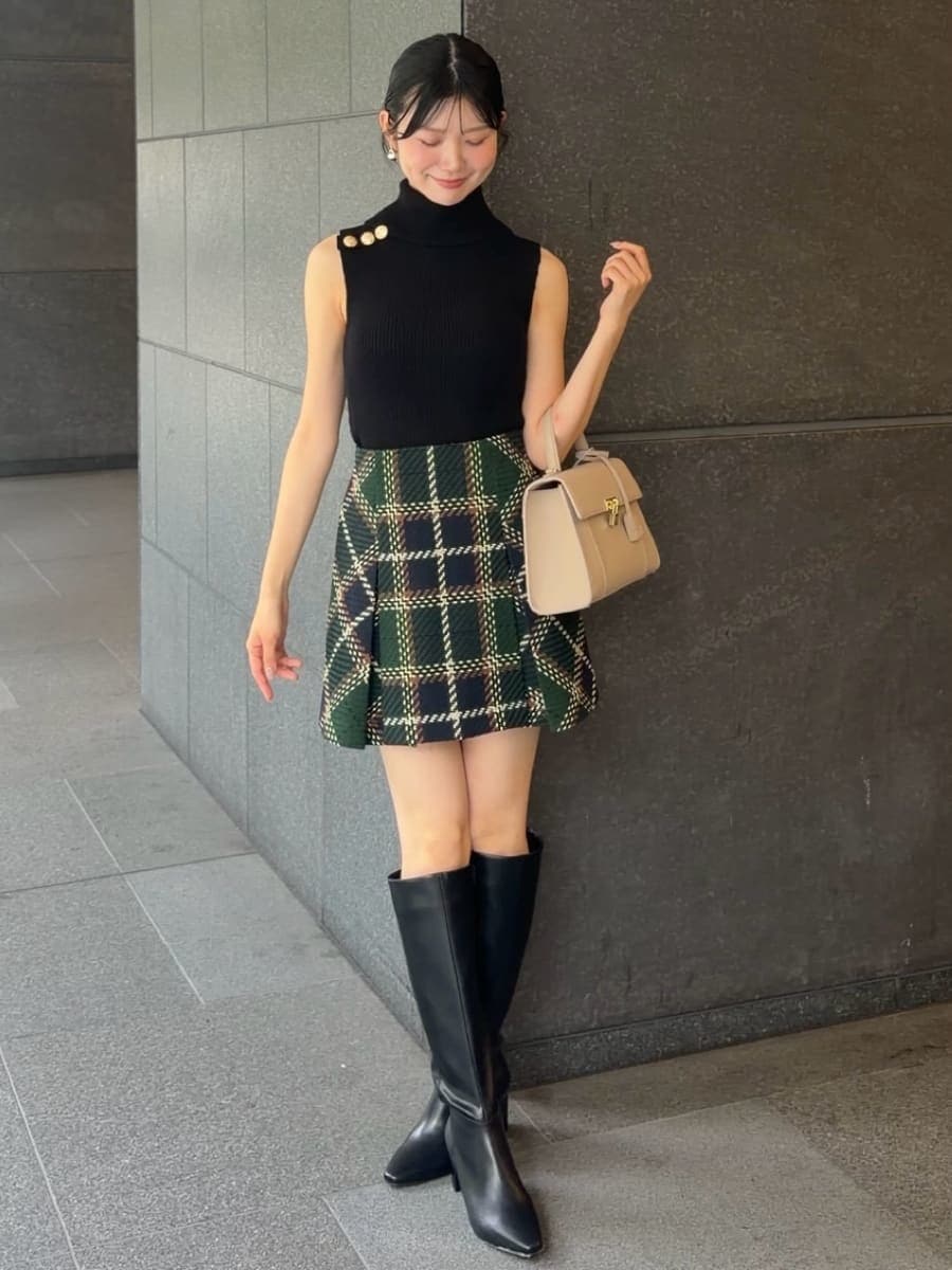 グリーン系のスカート、ブラック系のニット/セーター、ブラック系のブーツを着用したレディースの夏コーディネートの2枚目の写真