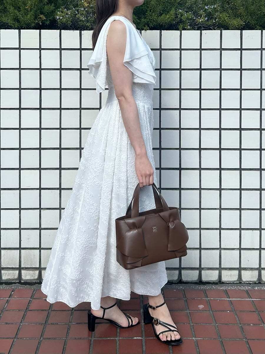 ホワイト系のワンピース、ブラウン系のハンドバッグ、ピンク系の折りたたみ傘を着用したレディースの春コーディネートの6枚目の写真