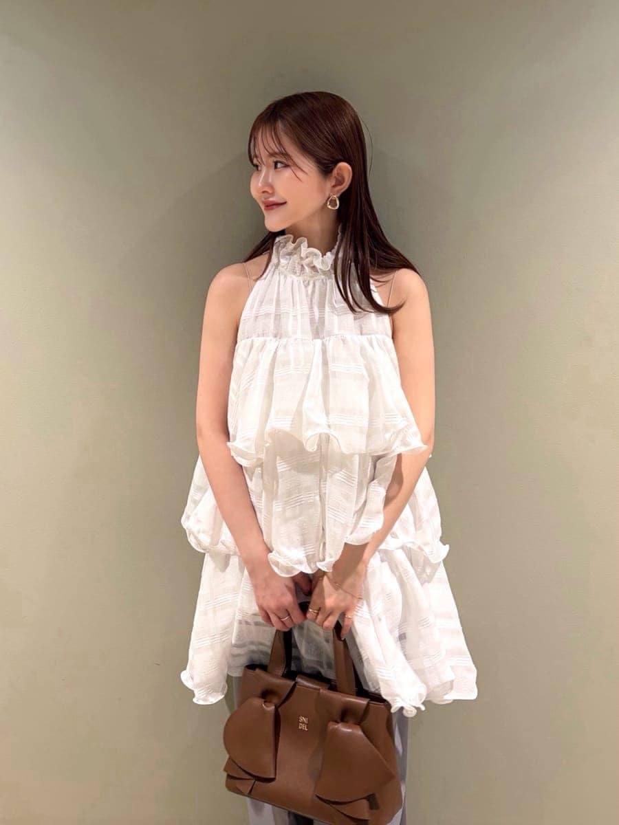 グレー系のスラックス、ホワイト系のワンピース、ブラウン系のパンプスを着用したレディースの春コーディネートの4枚目の写真