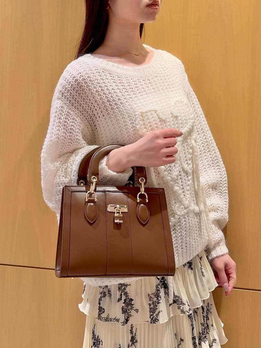 ホワイト系のニット/セーター、ブラウン系のハンドバッグ、イエロー系のスカートを着用したレディースの冬コーディネートの5枚目の写真