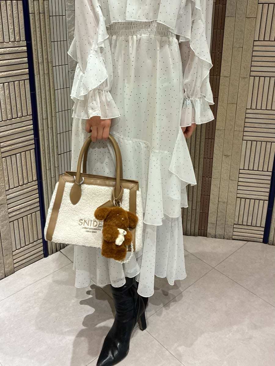 イエロー系のトートバッグ、ブラック系のブーツ、その他のワンピースを着用したレディースの冬コーディネートの7枚目の写真