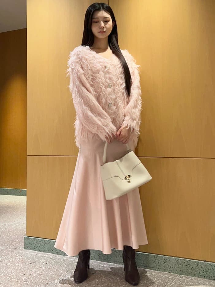 レッド系のブーツ、ピンク系のワンピース、ホワイト系のカーディガン/ボレロを着用したレディースの秋コーディネートの2枚目の写真