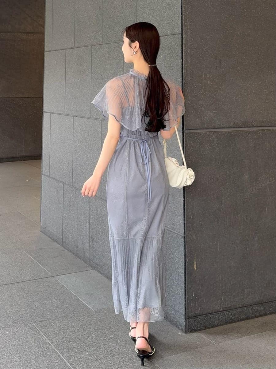 グレー系のドレス、ブラック系のパンプス、ホワイト系のハンドバッグを着用したレディースの春コーディネートの3枚目の写真