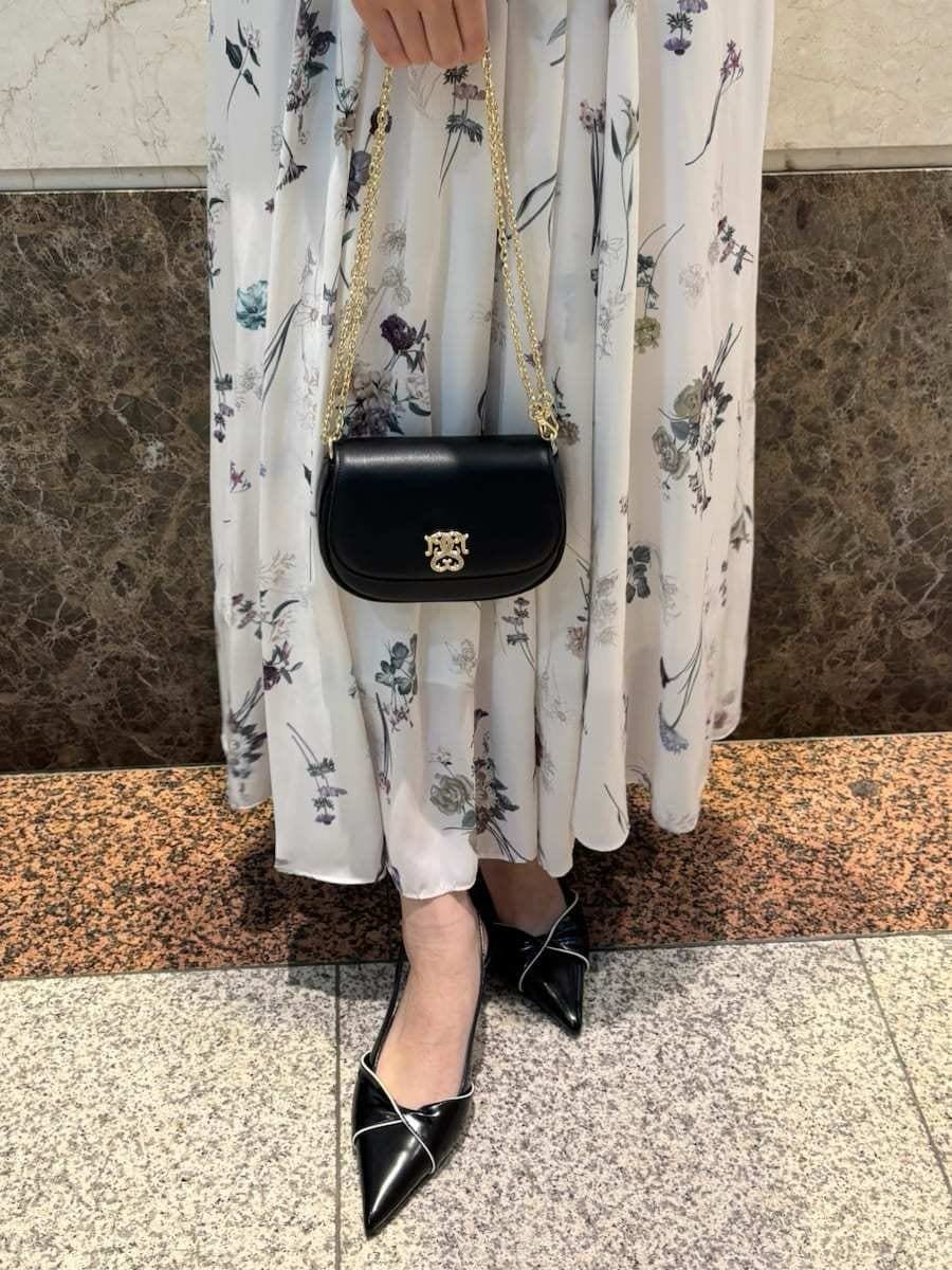 ホワイト系のワンピース、ブラック系のパンプス、ブラック系のショルダーバッグを着用したレディースの冬コーディネートの6枚目の写真