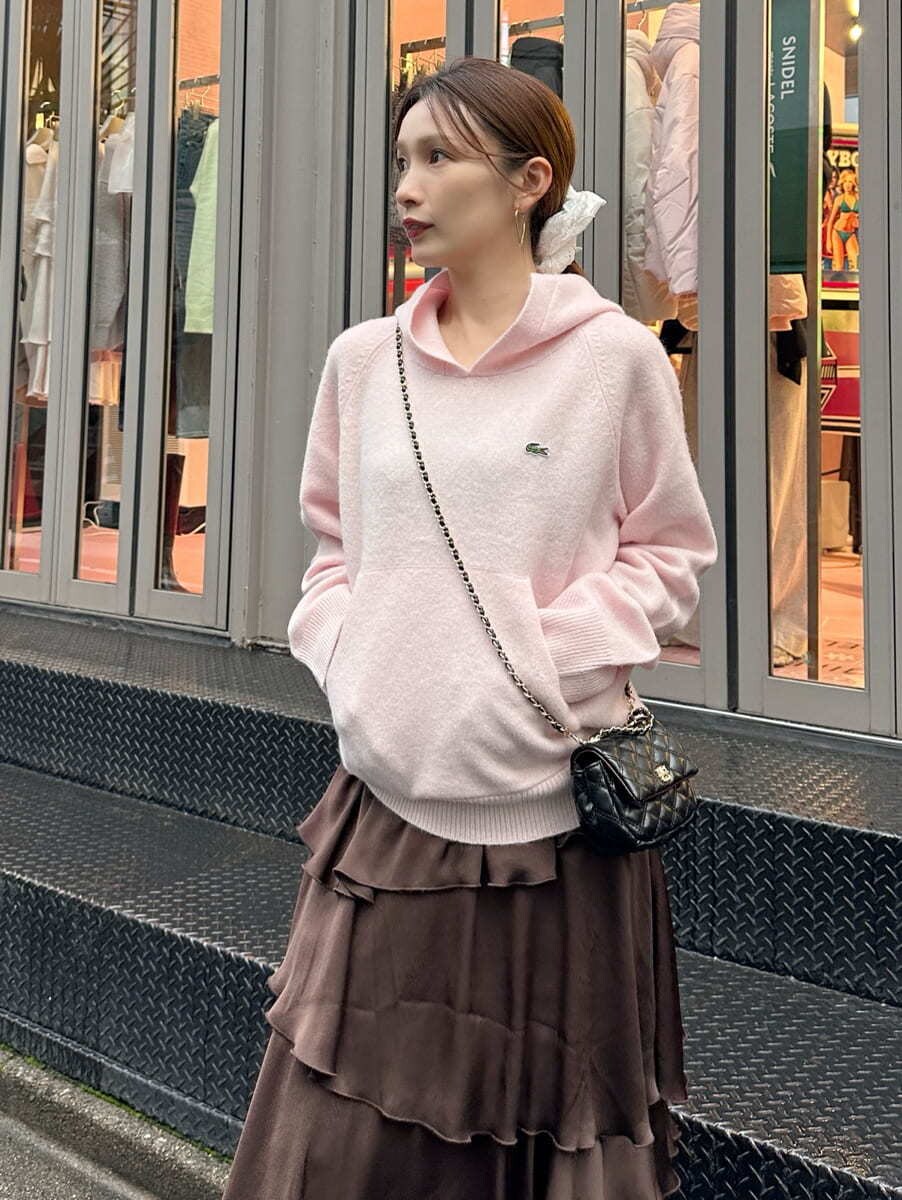 ピンク系のニット/セーター、ブラウン系のスカート、ブラック系のショルダーバッグを着用したレディースの秋コーディネートの2枚目の写真