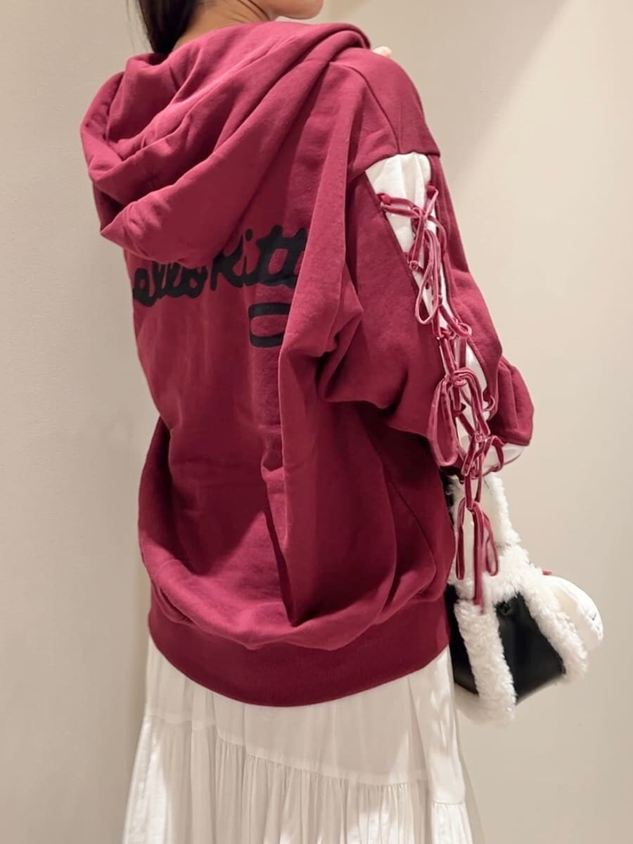 レッド系のパーカー、ホワイト系のスカート、ブラック系のハンドバッグを着用したレディースの秋コーディネートの3枚目の写真