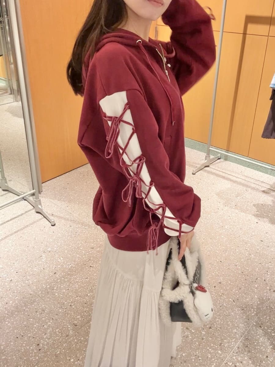 レッド系のパーカー、ホワイト系のスカート、ブラック系のハンドバッグを着用したレディースの秋コーディネートの5枚目の写真