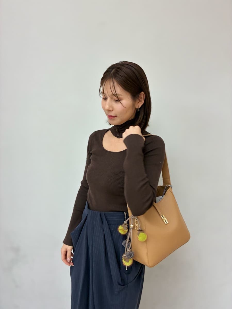 イエロー系のトートバッグ、グレー系のチェスターコート、ブルー系のその他パンツを着用したレディースの冬コーディネートの3枚目の写真