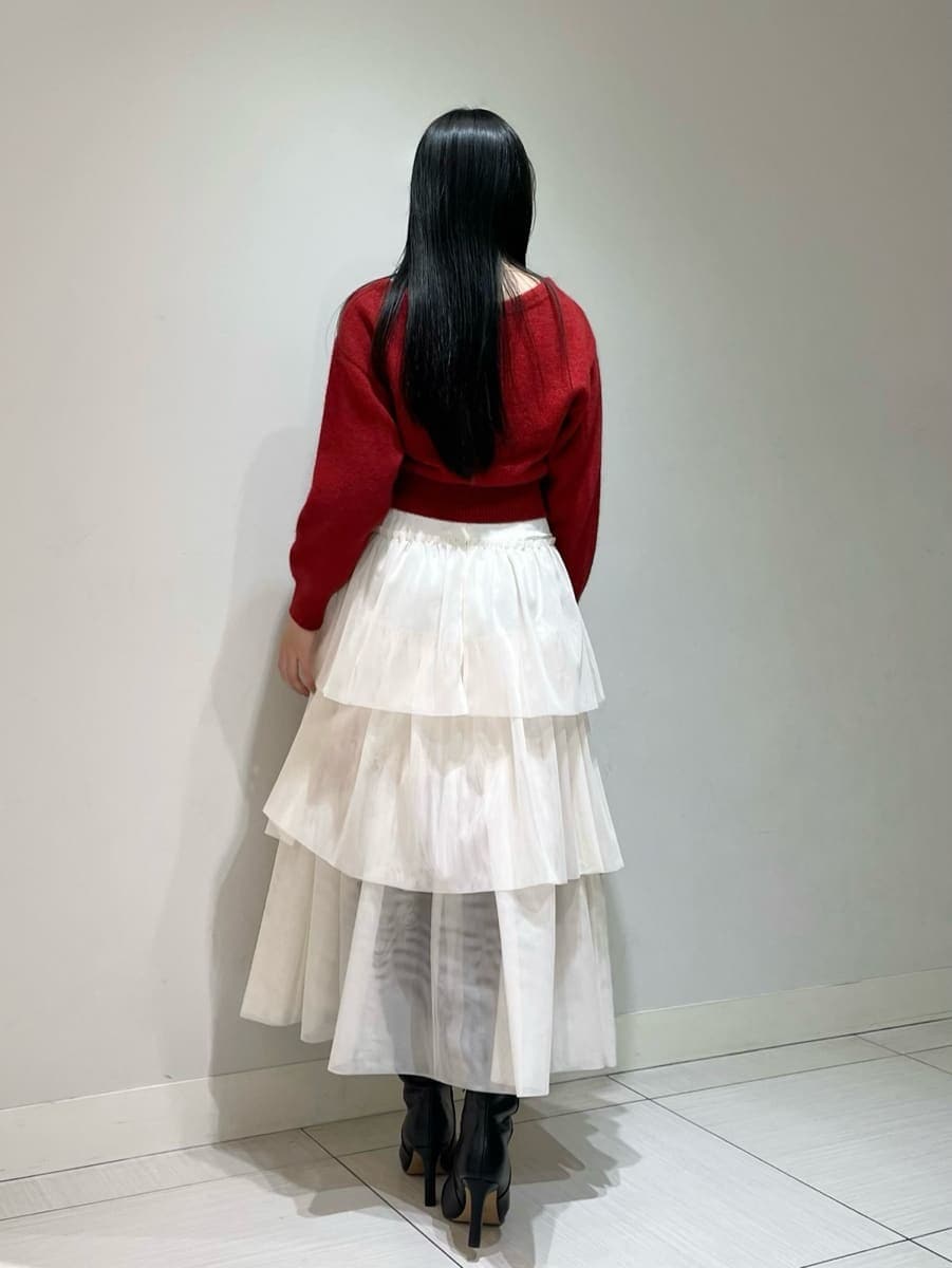 ブラック系のブーツ、ホワイト系のスカート、レッド系のカーディガン/ボレロを着用したレディースの冬コーディネートの3枚目の写真