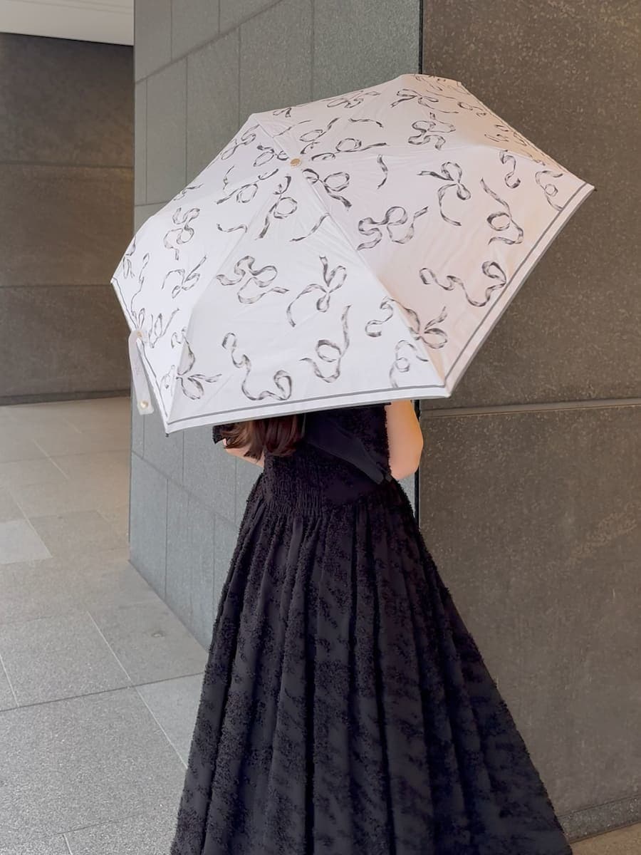 ブラック系のワンピース、ホワイト系のショルダーバッグ、ホワイト系の折りたたみ傘を着用したレディースの春コーディネートの8枚目の写真
