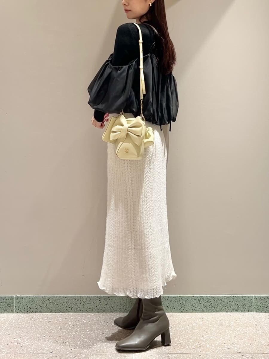 ホワイト系のスカート、ブラック系のニット/セーター、イエロー系のショルダーバッグを着用したレディースの秋コーディネートの2枚目の写真
