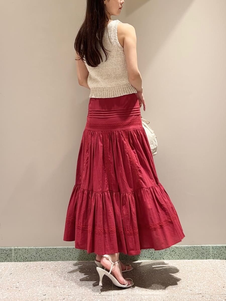 ホワイト系のニット/セーター、レッド系のスカート、ベージュ系のハンドバッグを着用したレディースの夏コーディネートの3枚目の写真