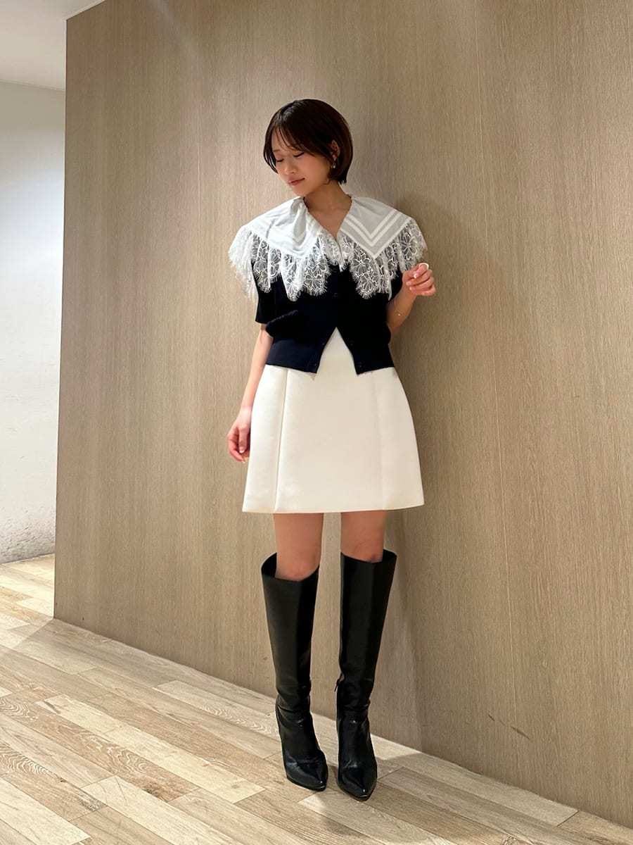 ブラック系のブーツ、ホワイト系のスカート、ブルー系のカーディガン/ボレロを着用したレディースの春コーディネートの2枚目の写真