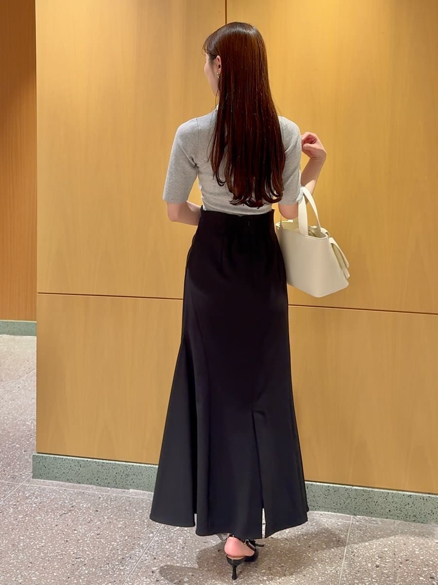 ブラック系のスカート、グレー系のニット/セーター、ホワイト系のハンドバッグを着用したレディースの春コーディネートの3枚目の写真