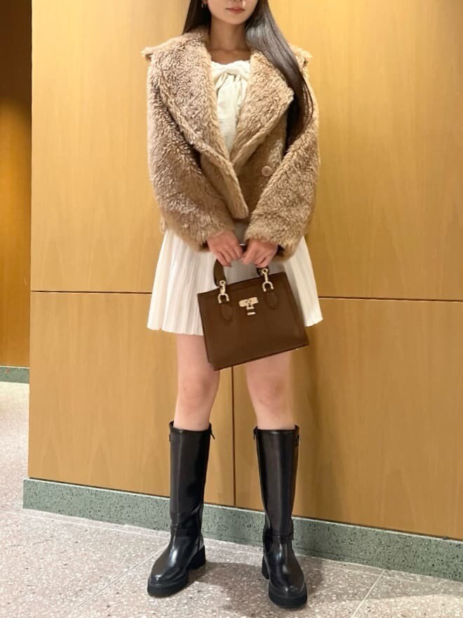 ブラック系のブーツ、ホワイト系のワンピース、ブラウン系のハンドバッグを着用したレディースの冬コーディネートの2枚目の写真