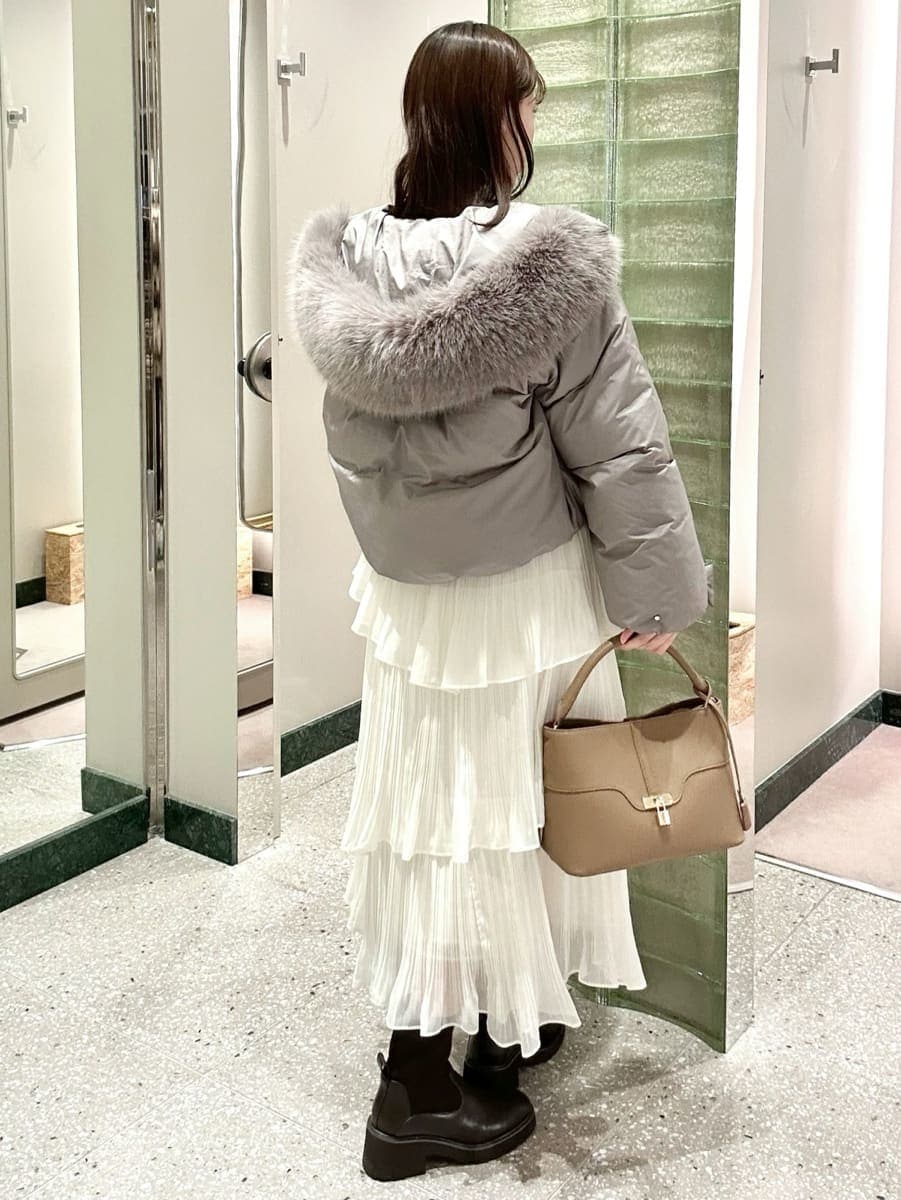 グレー系のダウンジャケット/コート、ホワイト系のスカート、その他のカーディガン/ボレロを着用したレディースの秋コーディネートの5枚目の写真