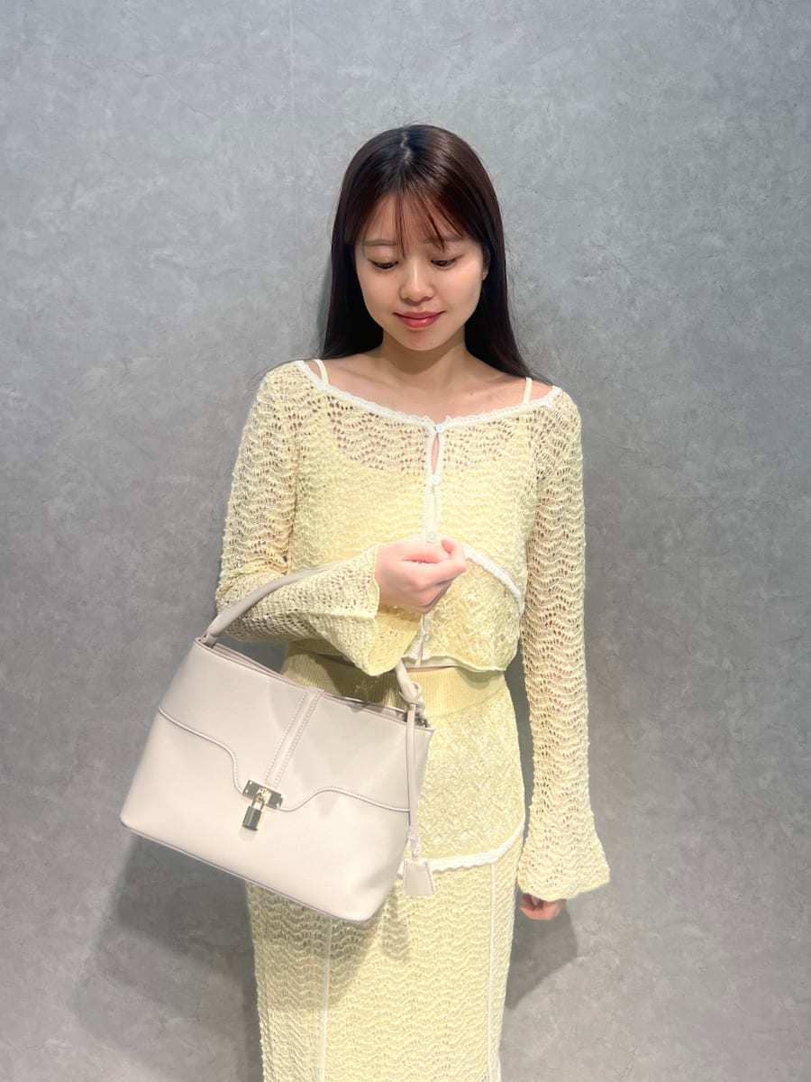 イエロー系のスカート、イエロー系のニット/セーター、ホワイト系のハンドバッグを着用したレディースの春コーディネートの4枚目の写真