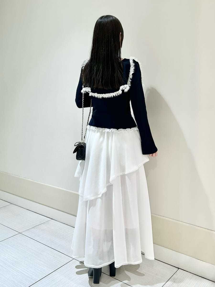 ブラック系のブーツ、ブラック系のショルダーバッグ、ホワイト系のスカートを着用したレディースの冬コーディネートの5枚目の写真