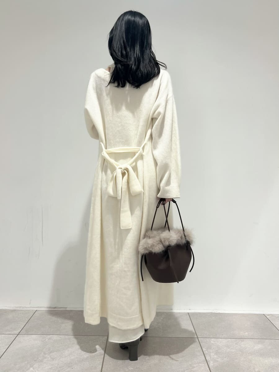 ホワイト系のチェスターコート、ホワイト系のワンピース、ブラウン系のハンドバッグを着用したレディースの冬コーディネートの3枚目の写真