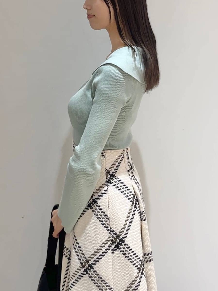 グリーン系のニット/セーター、ホワイト系のスカート、ブラック系のブーツを着用したレディースの秋コーディネートの6枚目の写真