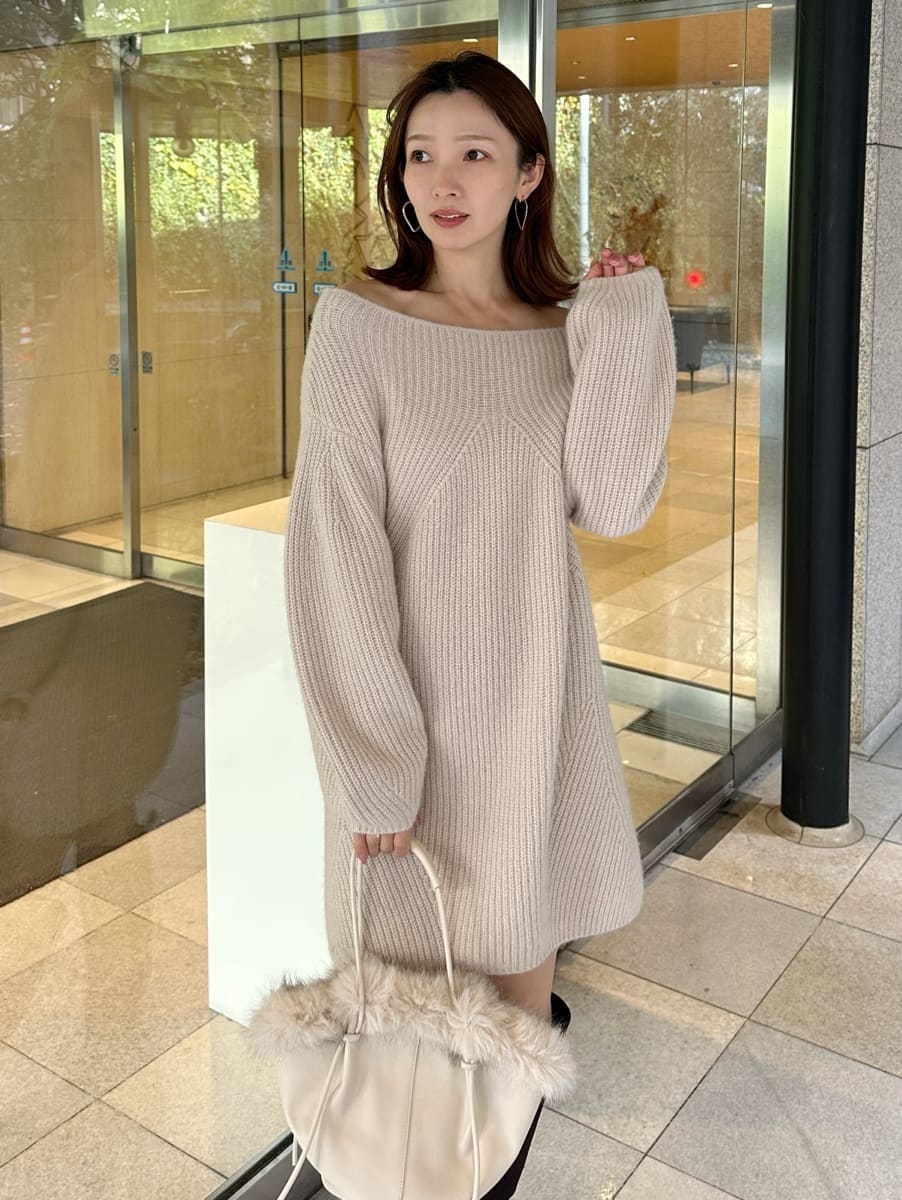 ホワイト系のハンドバッグ、ベージュ系のワンピースを着用したレディースの冬コーディネートの2枚目の写真