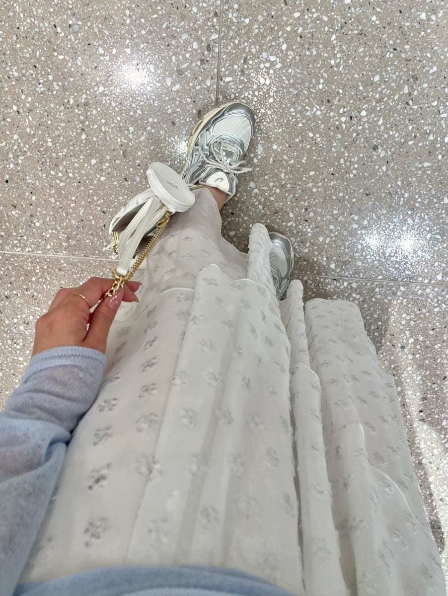 シルバー系のスカート、ブルー系のニット/セーター、ホワイト系のショルダーバッグを着用したレディースの冬コーディネートの5枚目の写真