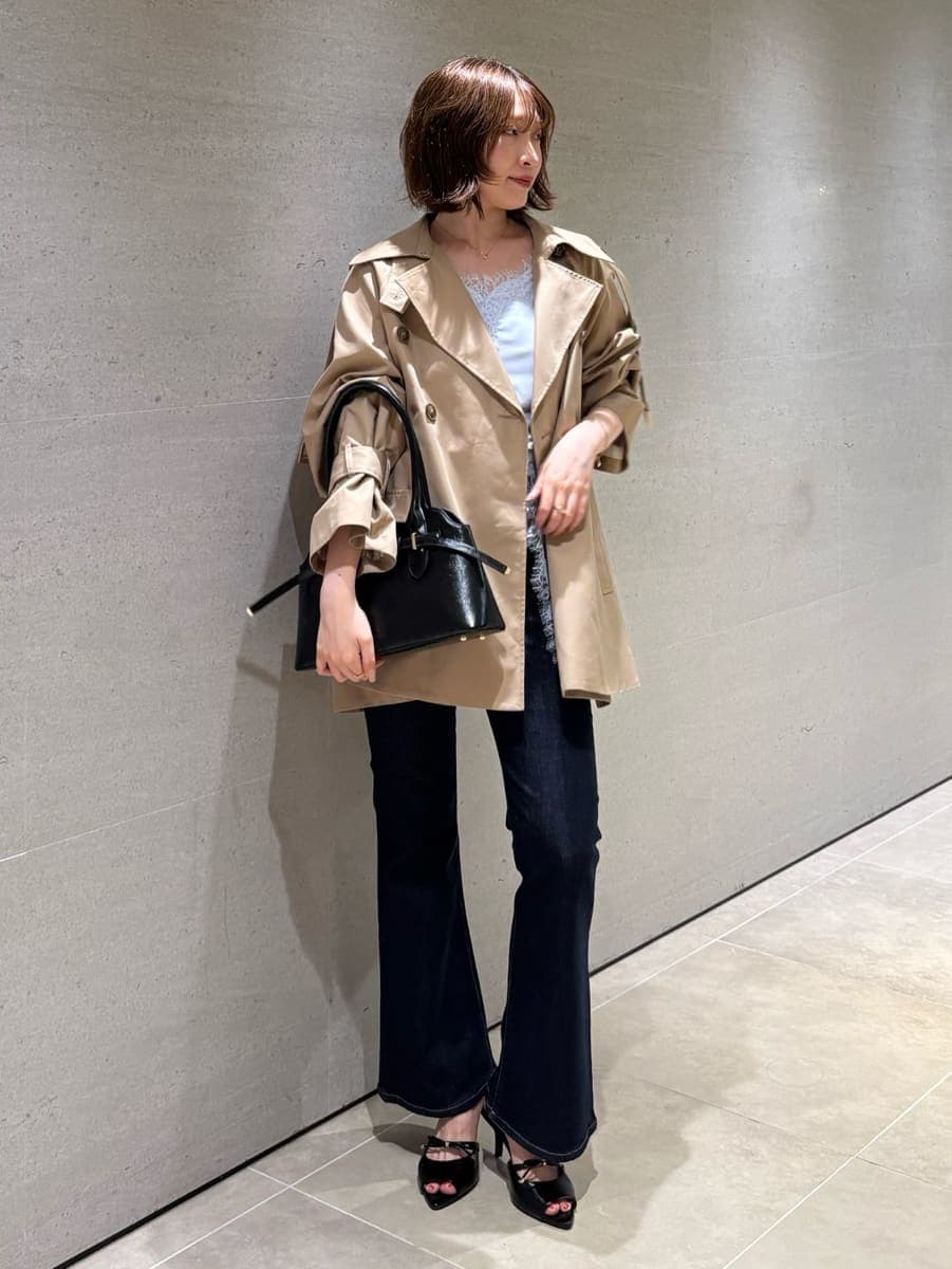 ブルー系のデニムパンツ、ベージュ系のトレンチコート、ブルー系のキャミソールを着用したレディースの秋コーディネートの2枚目の写真