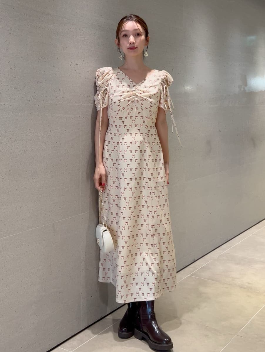 ホワイト系のトレンチコート、ベージュ系のワンピース、ホワイト系のショルダーバッグを着用したレディースの冬コーディネートの2枚目の写真