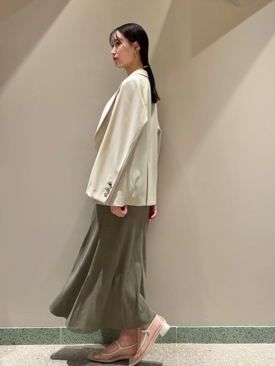 ベージュ系のテーラードジャケット、グリーン系のワンピース、ホワイト系のショルダーバッグを着用したレディースの夏コーディネートの3枚目の写真