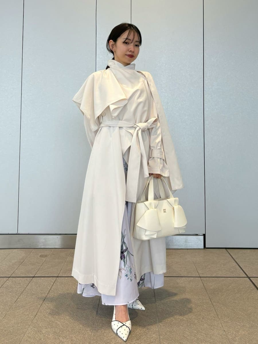 ホワイト系のトレンチコート、パープル系のワンピース、その他のパンプスを着用したレディースの冬コーディネートの6枚目の写真