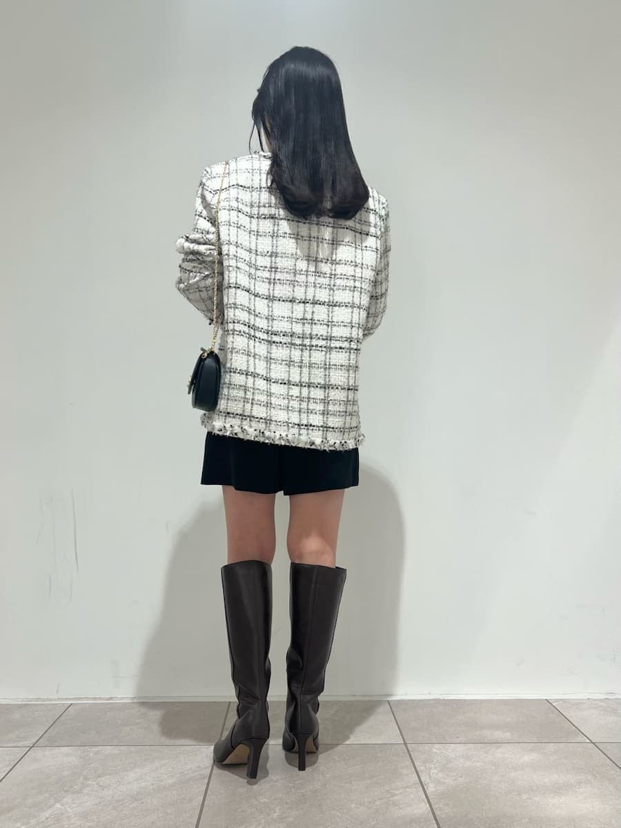 ブラウン系のブーツ、ホワイト系のノーカラージャケット、ブラック系のショルダーバッグを着用したレディースの冬コーディネートの3枚目の写真