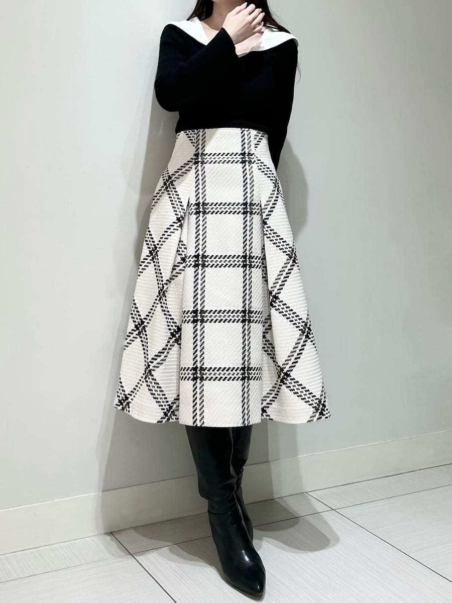 ブラック系のニット/セーター、ホワイト系のスカート、ブラック系のブーツを着用したレディースの秋コーディネートの3枚目の写真
